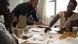 Three people sit working around a table