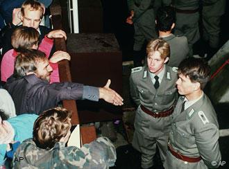 East German border policemen refuse to shake hands with a Berliner who stretches out his hand over the border fence at the eastern site nearby Checkpoint Charlie border crossing point, in this Nov. 10, 1989