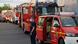 Convoy of fire trucks, man stands at an open car door 